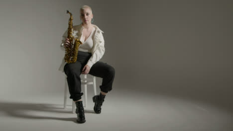 Schiebeaufnahme-Eines-Models,-Das-Mit-Saxophon-Vor-Grauem-Hintergrund-Posiert