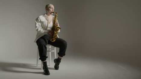 Wide-Shot-of-Model-Playing-Saxophone-Against-Grey-Backdrop