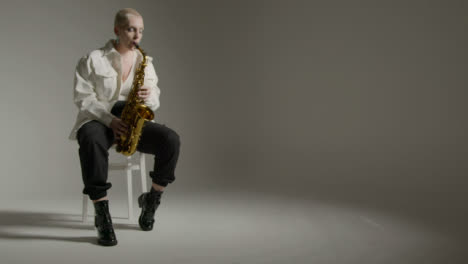 Sliding-Shot-of-Model-Playing-Saxophone-Against-Grey-Backdrop