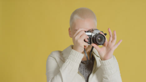 Female-caucasian-model-posing-with-vintage-SLR-against-yellow-backdrop-01