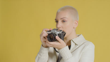Female-caucasian-model-posing-with-vintage-SLR-against-yellow-backdrop-02