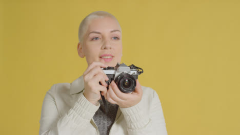 Female-caucasian-model-posing-with-vintage-SLR-against-yellow-backdrop-03