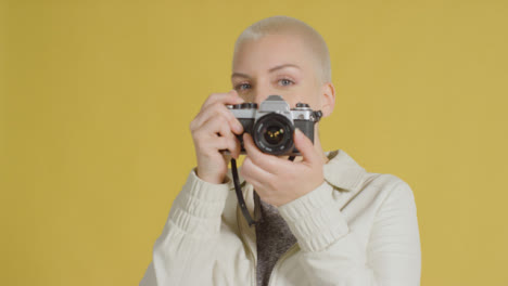 Female-caucasian-model-posing-with-vintage-SLR-against-yellow-backdrop-04