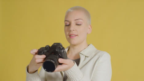 Female-caucasian-model-posing-with-DSLR-against-yellow-backdrop-01