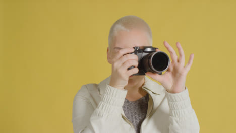 Female-caucasian-model-posing-with-DSLR-against-yellow-backdrop-02