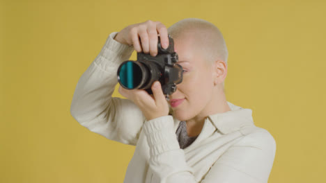Female-caucasian-model-posing-with-DSLR-against-yellow-backdrop-03