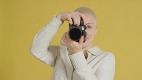 Female-caucasian-model-posing-with-DSLR-against-yellow-backdrop-05