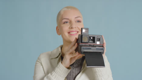 Female-caucasian-model-posing-with-instant-film-camera-against-blue-backdrop-01
