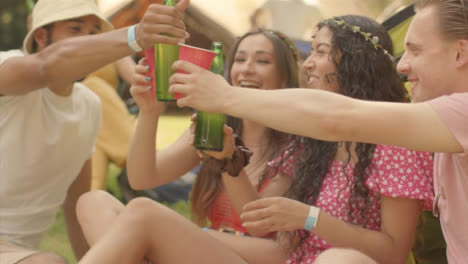 Kamerafahrt-Um-Eine-Gruppe-Junger-Festivalbesucher-Herum,-Während-Einer-Getränke-Vorbeibringt?