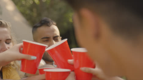 Over-the-Shoulder-Shot-of-Group-of-Friends-Bringing-Their-Drinks-Together-In-a-Toast