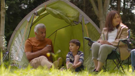 Low-Angle-Shot-of-Young-Children-Sitting-with-Grandparents-On-Camping-Trip