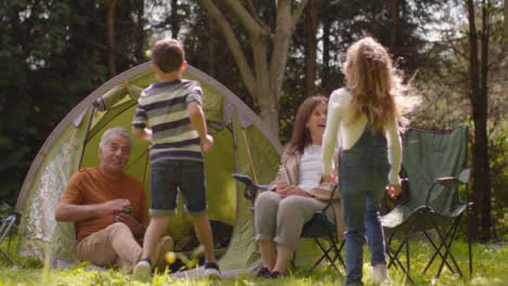 Low-Angle-Shot-of-Young-Children-Running-to-Join-Grandparents-On-Camping-Trip