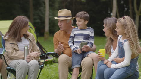 Tracking-Shot-of-Family-On-Camping-Trip-Sitting-and-Talking-by-Their-Tents-03