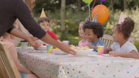 Medium-Shot-of-Children-Sitting-at-Table-at-Outdoor-Birthday-Party-