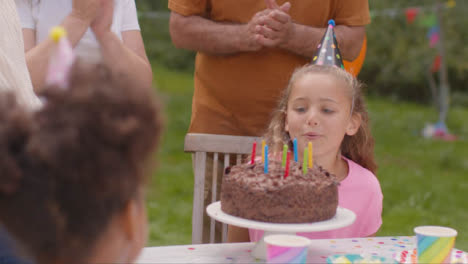 Disparo-Por-Encima-Del-Hombro-De-La-Niña-Soplando-Velas-En-La-Fiesta-De-Cumpleaños