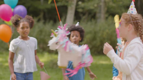 Mittlere-Aufnahme-Eines-Jungen-Mädchens,-Das-Auf-Einer-Geburtstagsfeier-An-Einer-Pinata-Schwingt