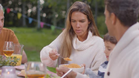 Tracking-Shot-of-Mother-Serving-Dinner-to-Young-Son-During-Family-Outdoor-Dinner