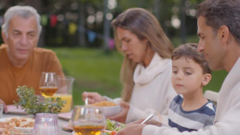 Tracking-Shot-of-Family-Serving-Up-Food-During-Outdoor-Dinner-01
