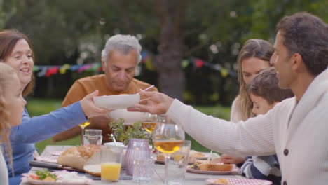 Tracking-Shot-of-Family-Serving-Up-Food-During-Outdoor-Dinner-03