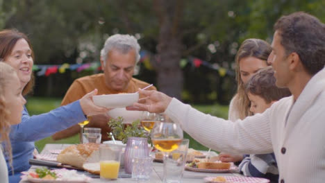 Kamerafahrt-Einer-Familie,-Die-Während-Des-Abendessens-Im-Freien-Essen-Serviert-03