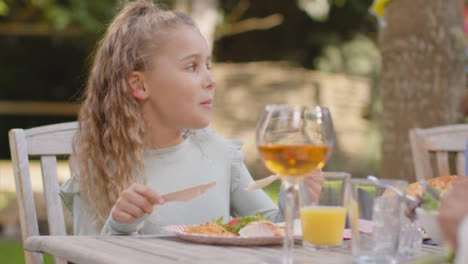 Close-Up-Shot-of-Young-Girl-Eating-Outdoor-Dinner-with-Family-