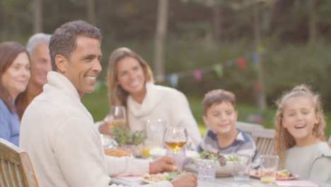 Tracking-Shot-of-Family-at-Outdoor-Dinner-Table-Smiling-