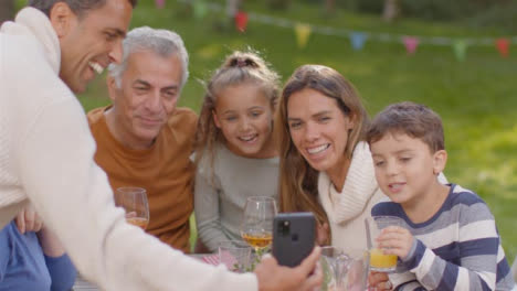 Over-the-Shoulder-Shot-of-Family-Taking-Selfie-at-Outdoor-Dinner-Table-01
