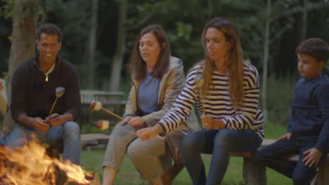 Sliding-Shot-of-Family-Sitting-Around-Campfire
