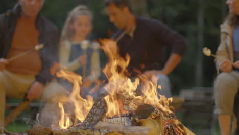 Pull-Focus-Shot-from-Father,-Grandfather-and-Daughter-to-Campfire