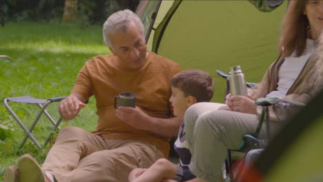 Handheld-Shot-of-Grandparents-and-Grandchildren-Sitting-by-Tents