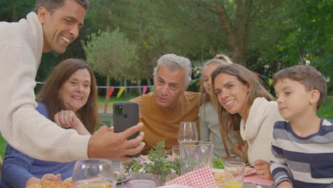 Handheld-Shot-of-Family-Talking-to-Someone-Via-Phone-Video-Call-During-Al-Fresco-Dinner-01