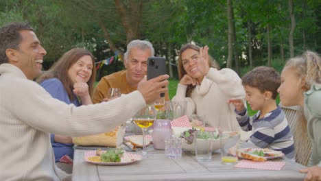 Handheld-Shot-of-Family-Talking-to-Someone-Via-Phone-Video-Call-During-Al-Fresco-Dinner-02