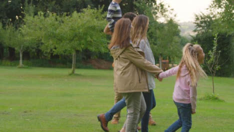 Handheld-Shot-of-Family-Walking-Through-Gardens-Talking-and-Laughing-