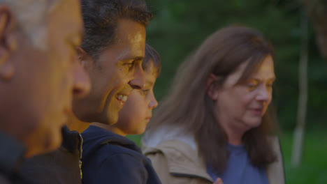 Over-the-Shoulder-Shot-of-Family-Sitting-Around-Campfire