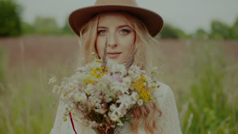 Young-Beautiful-Hippie-Boho-Woman-Looking-Into-Camera-While-Holding-Flowers-In-Hands