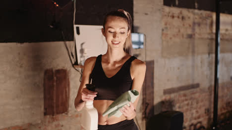 Slow-Motion-Of-Smiling-Young-Woman-Spraying-Water-On-Cloth-In-Gym