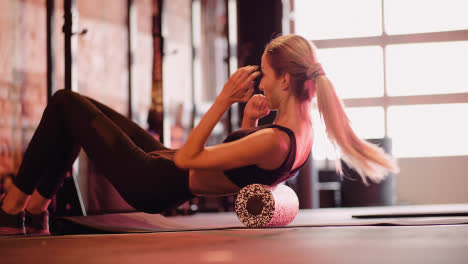 Lockdown-Shot-Of-Young-Woman-Exercising-With-Foam-Roller-At-Fitness-Club