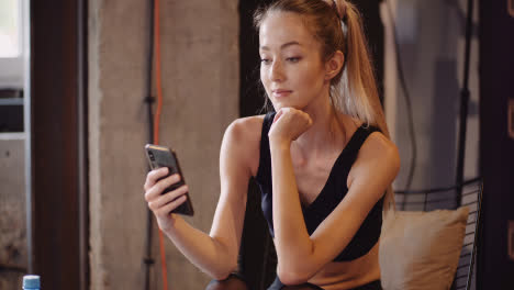Lockdown-Shot-Of-Woman-Using-Mobile-Phone-While-Relaxing-After-Workout-Session