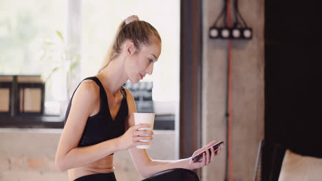 Lockdown-Shot-Of-Attractive-Young-Woman-Using-Smartphone-While-Relaxing-After-Workout-Session