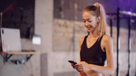 Attraktive-Junge-Sportliche-Frau-Textnachrichten-über-Handy-Während-Der-Pause-Im-Fitnessclub