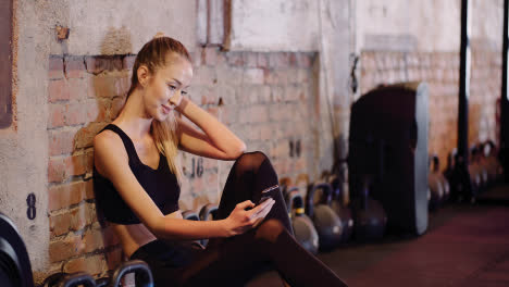 Beautiful-Female-Athlete-Text-Messaging-Through-Mobile-Phone-During-Break-At-Health-Studio-3