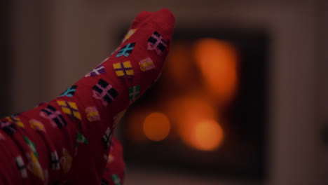 Young-Woman-Wearing-Warm-Wool-Socks-Lying-By-The-Fireplace-At-Christmas-Eve-2