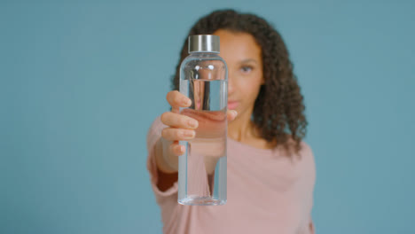 Retrato-De-Mujer-Adulta-Joven-Bebiendo-Mostrando-Una-Botella-De-Agua-A-La-Cámara-02