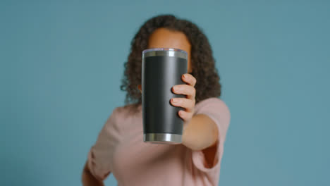 Portrait-Shot-of-Young-Adult-Woman-Holding-Up-Flask-to-Camera