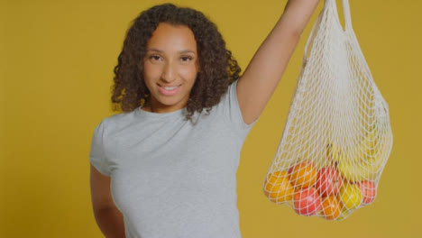 Portrait-Shot-of-Young-Adult-Woman-Holding-Up-Bag-of-Fruit