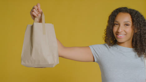 Portrait-Shot-of-Young-Adult-Woman-Holding-Up-Brown-Paper-Bag-with-Copy-Space