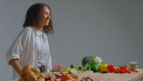 Weitschuss-Einer-Jungen-Erwachsenen-Frau,-Die-Zucchini-Schneidet,-Bevor-Sie-Aus-Der-Kamera-Lacht