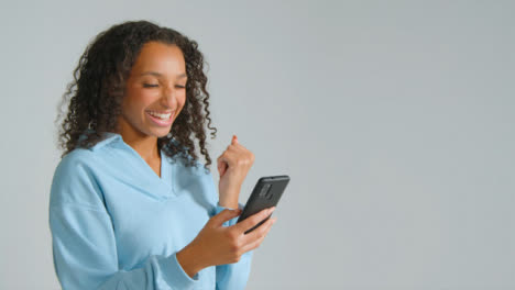 Portrait-Shot-of-Young-Adult-Woman-Smiling-at-Her-Smartphone