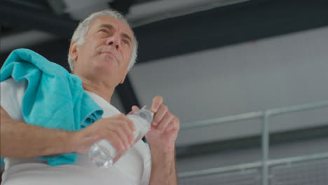 Flachwinkelaufnahme-Eines-älteren-Mannes,-Der-Aus-Einer-Plastikwasserflasche-Trinkt