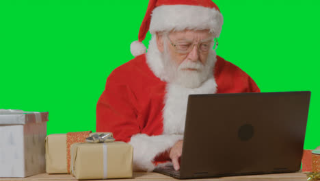 Portrait-Shot-of-Santa-Using-Laptop-In-Front-of-Green-Screen